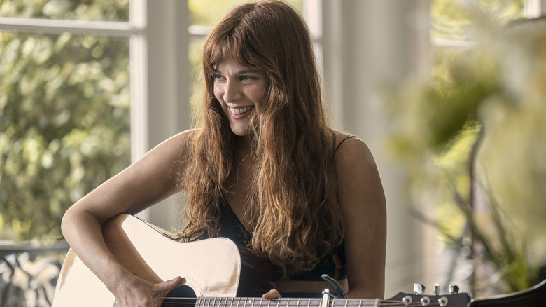 Daisy smiles and plays guitar