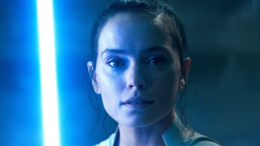 Rey smiling with lightsaber