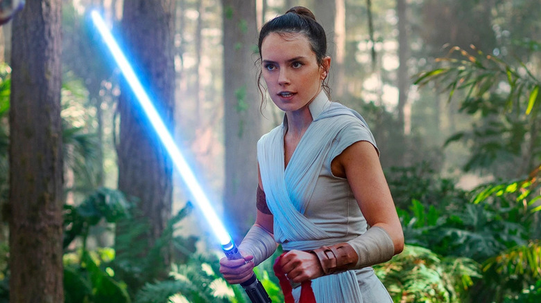 Rey holds a bright blue lightsaber