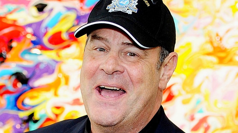 Dan Aykroyd wears a cap and smiles