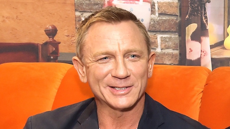 Daniel Craig sitting on orange couch