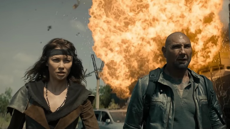 Drea and Jake walking toward the camera, away from a massive explosion, in Afterburn