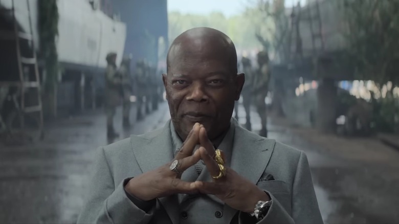 King sitting in a warehouse with lines of army men behind him, his fingers steepled, in Afterburn