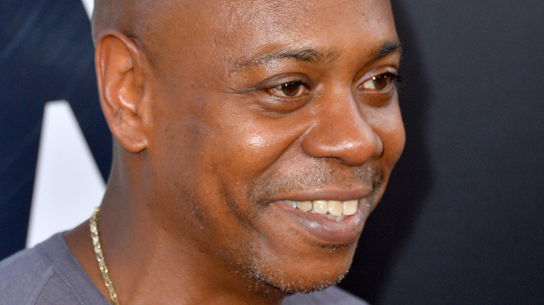 Dave Chappelle smiling and looking off camera