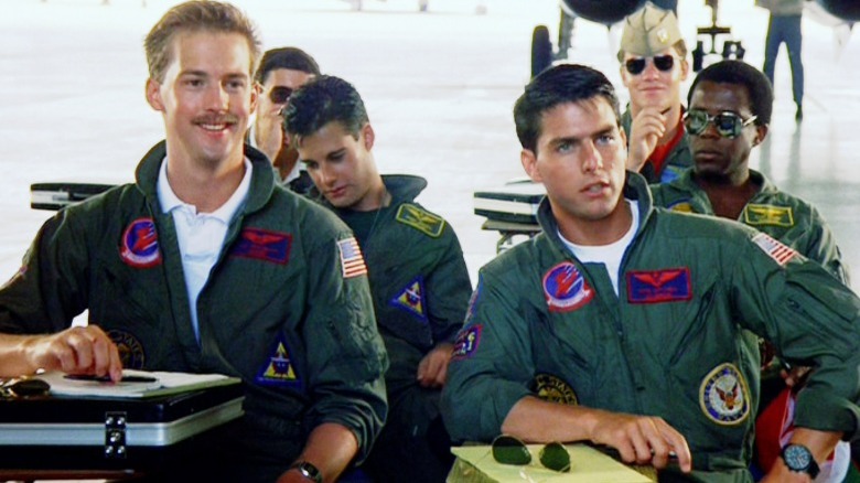 The cast of Top Gun sitting down in a hangar