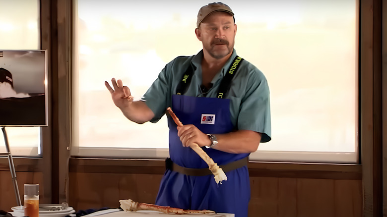 Keith Colburn holding crab leg and wearing apron