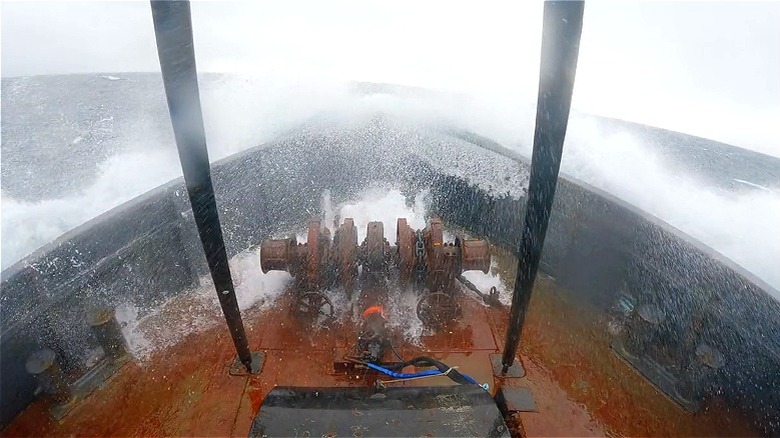 Water crests over the front of a boat 