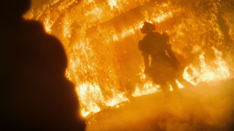 Pennywise the Dancing Clown standing in front of a building fire on It: Welcome to Derry