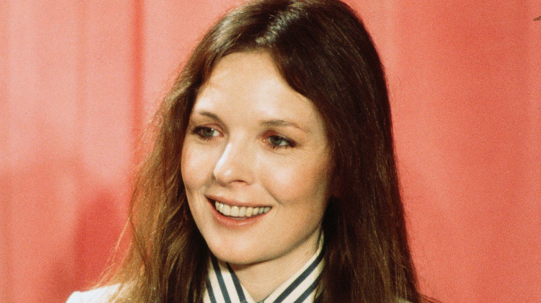Diane Keaton smiling in front of a peach curtain