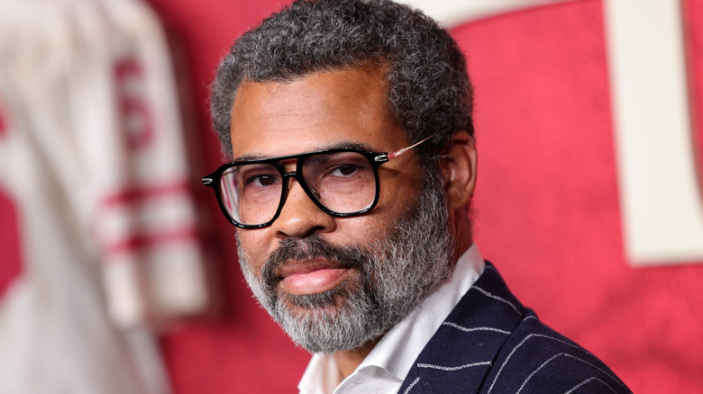 Jordan Peele wearing glasses and looking serious