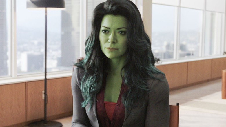 Jennifer Hulk mode sitting in office staring red shirt