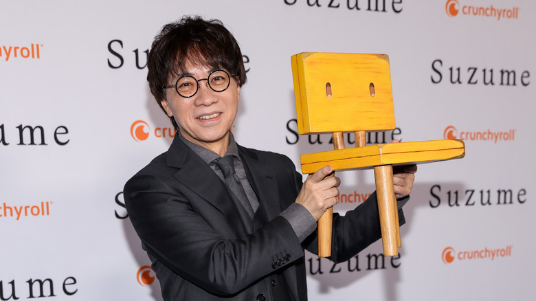 Makoto Shinkai holds the chair from Suzume