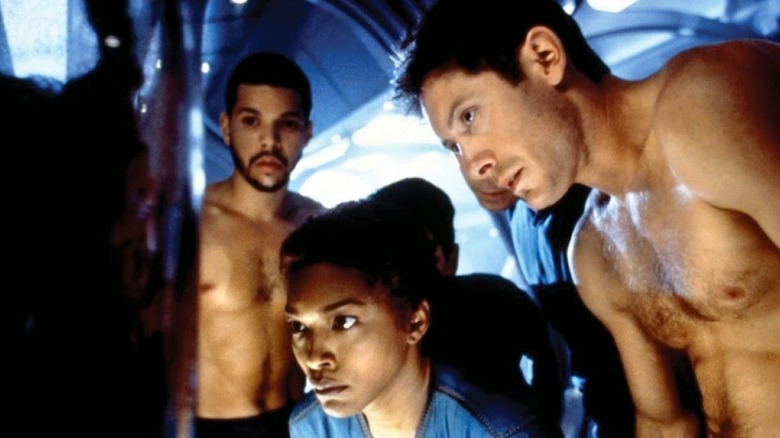 Shirtless astronauts inspecting a screen in "Supernova" (2000)