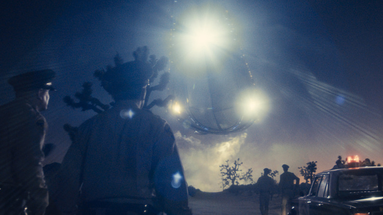 Police officers staring up at the bright lights of a UFO in "Disclosure Day" (2026)