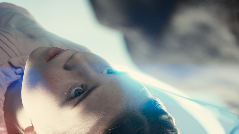A young Margaret looking up at the face of an alien from a lab table in "Disclosure Day" (2026)