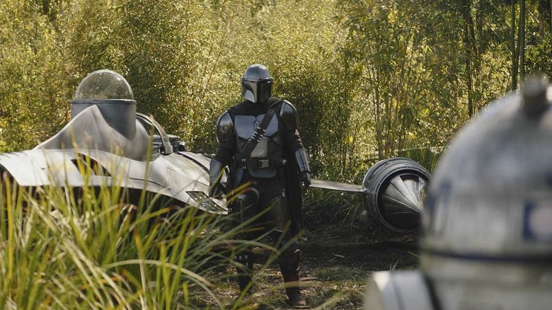 Din Djarin staring at R2-D2 after dismounting his N1 starship on Ossus in The Book of Boba Fett
