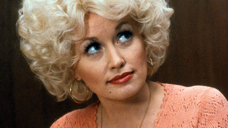 Doralee looking up in an orange sweater in 9 to 5
