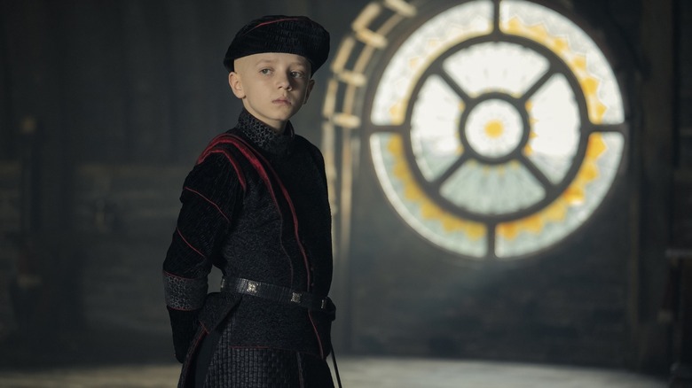 Egg wearing a cap and Targaryen garb in front of a window on A Knight of the Seven Kingdoms