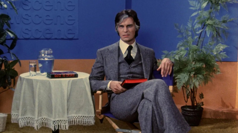 Hanson sits in a chair on the set of his TV show
