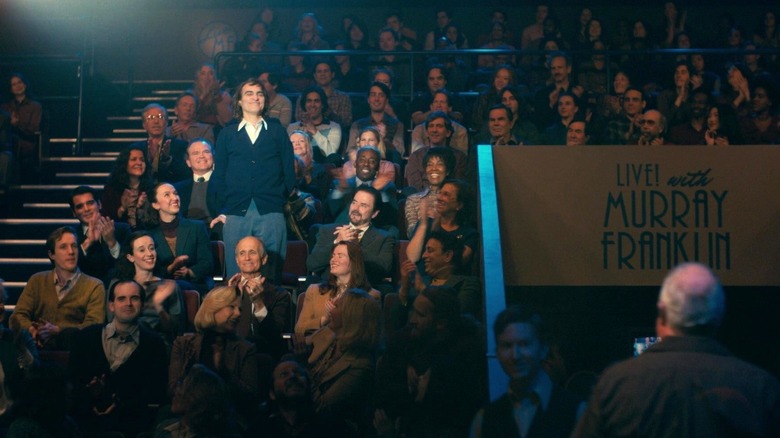 Arthur Fleck standing up and smiling on "Live! with Murray Franklin" in "Joker" (2019)