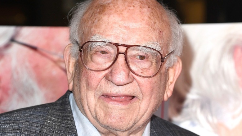 Ed Asner wearing glasses and smiling