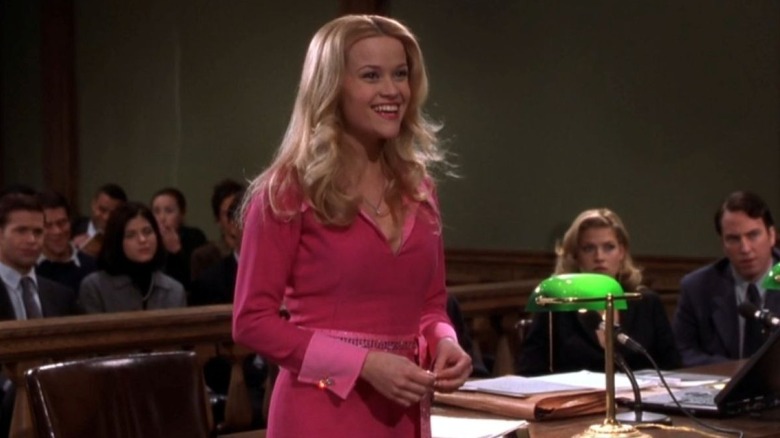 Elle smiles while standing in a courtroom in "Legally Blonde" (2001)