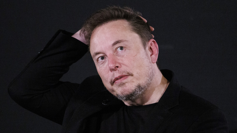 Elon Musk rubbing his head