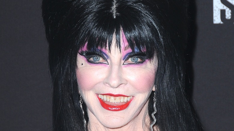 Elvira in wig and purple eye makeup smiling