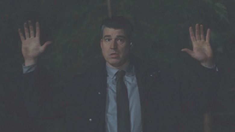 a man holds his hands in the air at gunpoint