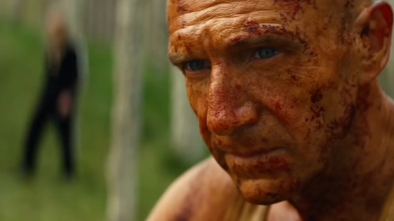 Dr. Ian Kelson sitting down with Jimmy lurking in the background in 28 Years Later: The Bone Temple