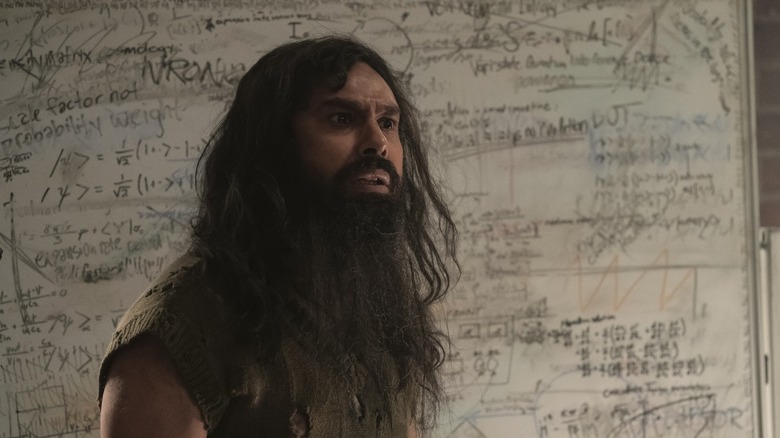 Raj with a long beard in front of a whiteboard in Stuart Fails to Save the Universe