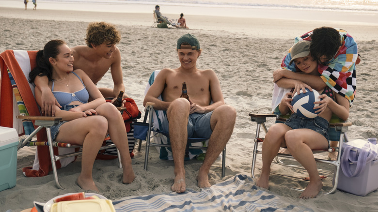 Belly, Jeremiah, Conrad, Taylor, and Steven sitting on the beach in 