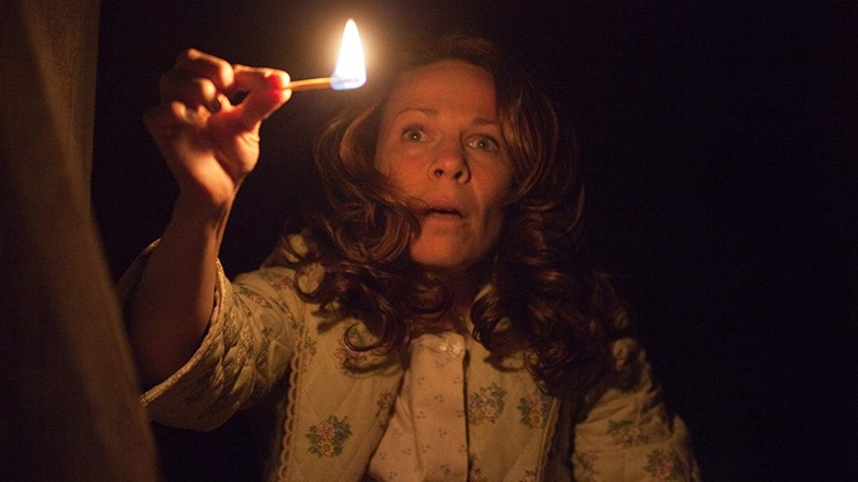 Woman holds match in darkness