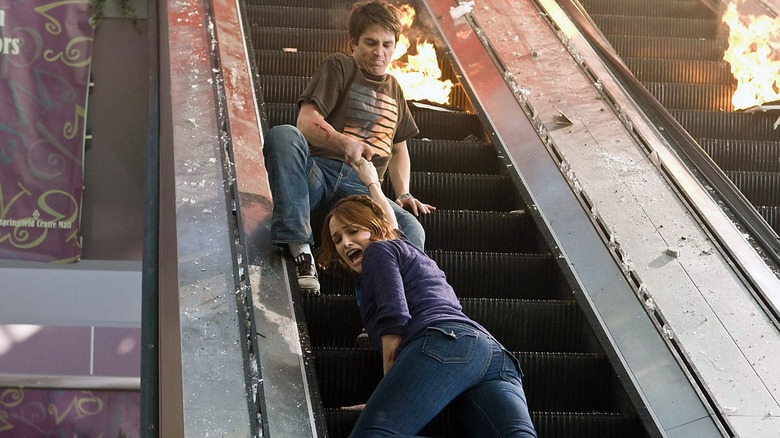 Two twenty-somethings hang onto an escalator in "The Final Destination" (2009)