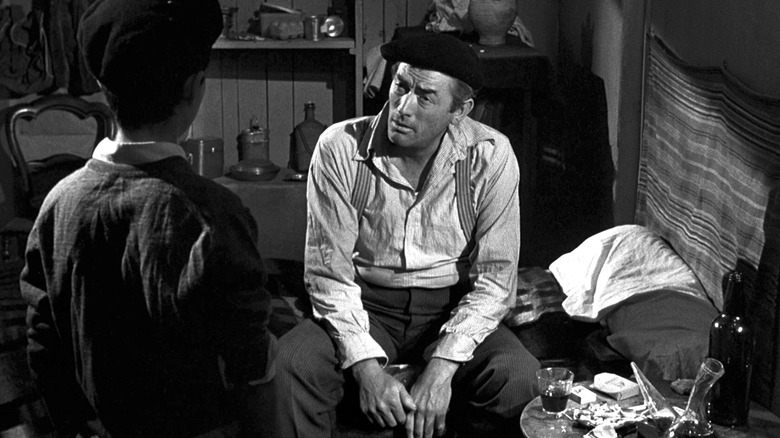 Peck sits on a bed and talks to a boy