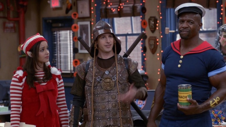 Amy Santiago, Jake Peralta, and Terry Jeffords look on in Halloween costumes