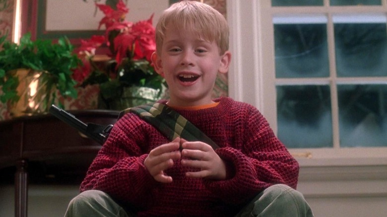 Kevin sits with his BB gun and smiles in Home Alone (1990)