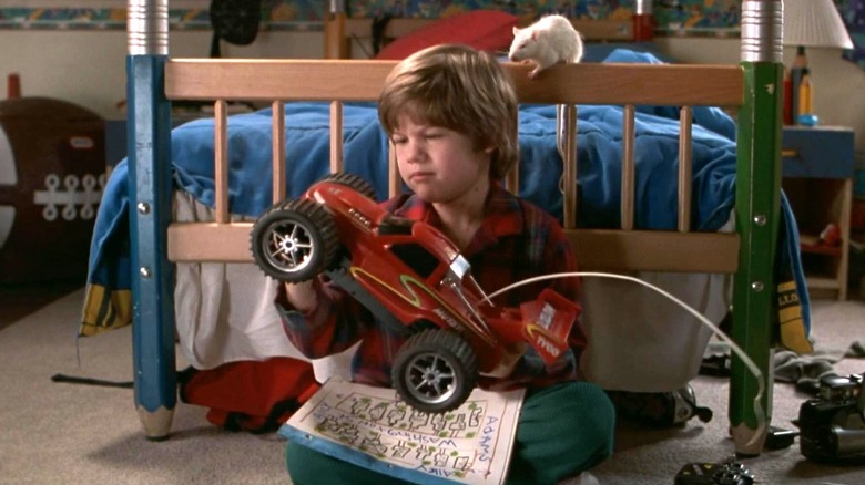 Alex holds a toy car while his pet rat sits behind him in Home Alone 3 (1997)