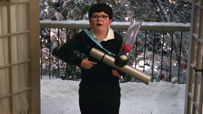 Max stands on a snowy porch with a ball shooter in Home Sweet Home Alone (2021)