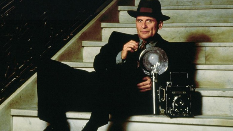 Leon Bernstein posing with his camera on stairs in 1992's The Public Eye