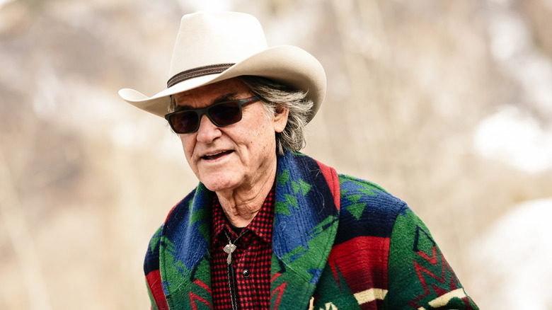 Kurt Russell wearing a cowboy hat and a cardigan