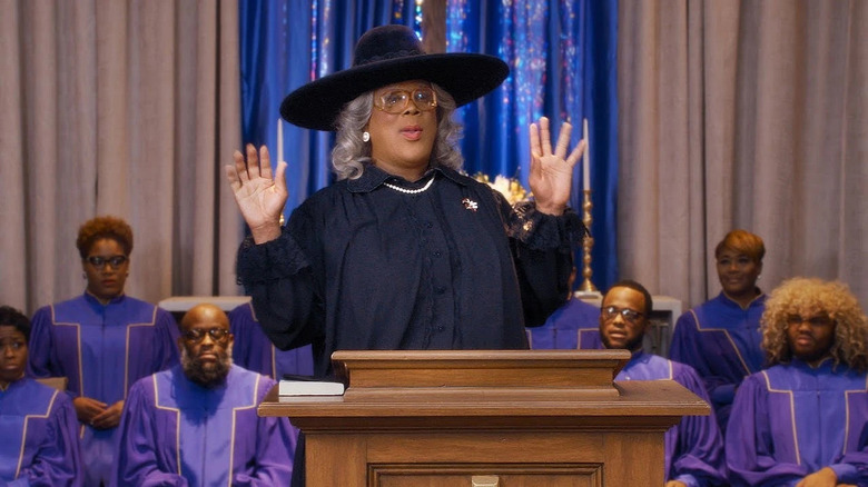 Madea speaking at a funeral with a choir behind her