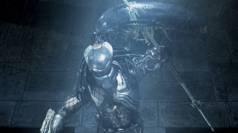 A Predator holds up the head of a Xenomorph in Alien vs Predator