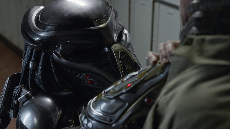 A Predator holds a man by the neck in The Predator