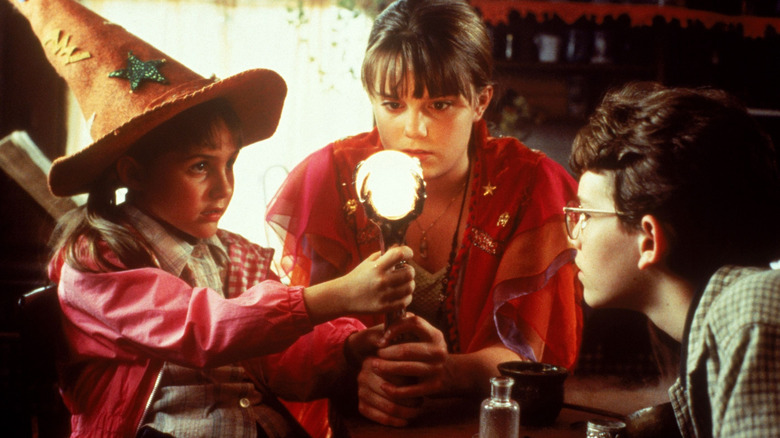 Three kids gathering around a glowing orb in Halloweentown (1998)