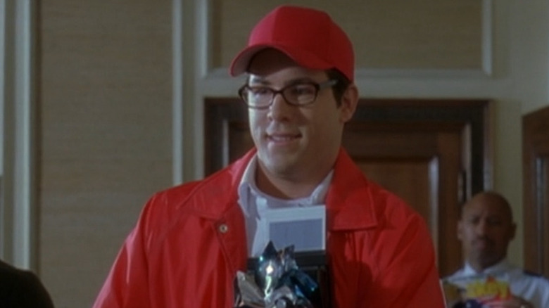 Ryan Reynolds in a red outfit holds a pile of objects