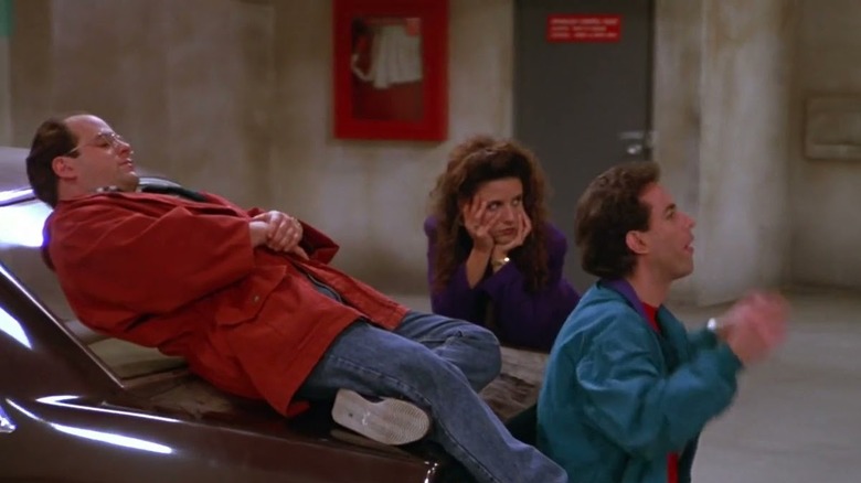 George Elaine and Jerry resting on a car