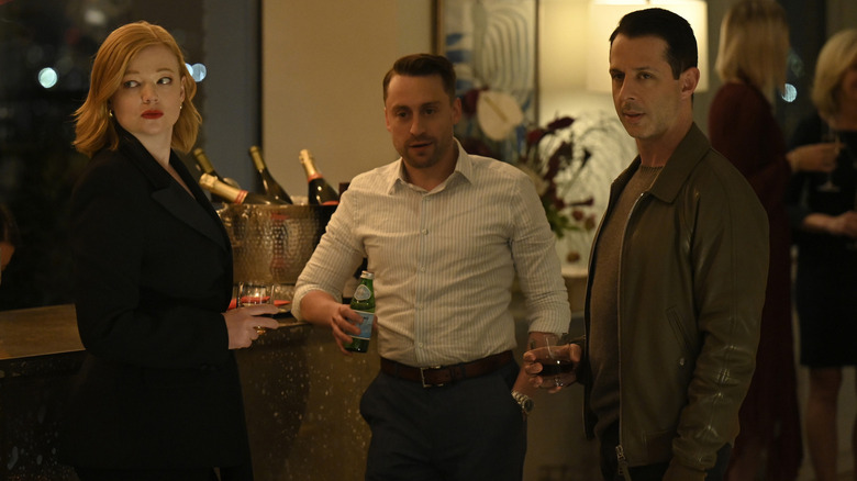 Shiv Roman and Kendall at a party looking at someone on Succession