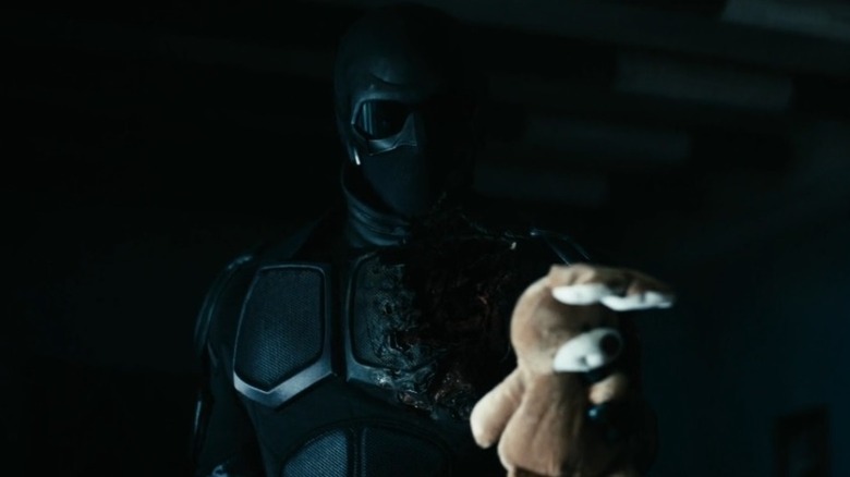 Black Noir handing a stuffed animal over