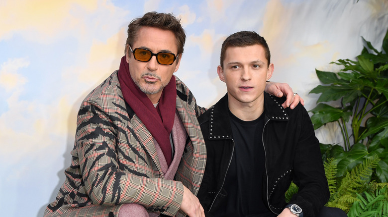 Robert Downey Jr. and Tom Holland crouch together at a premiere